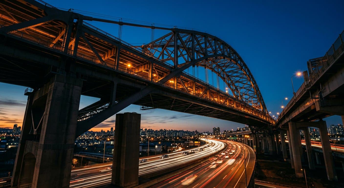 Large steel bridge at dusk with structural beams and warm lights
